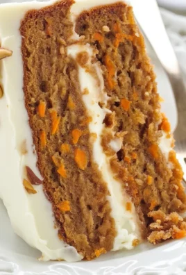 Slice of the best carrot cake with cream cheese frosting and chopped nuts