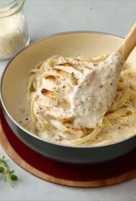 Creamy homemade Alfredo Sauce drizzled over fettuccine pasta.