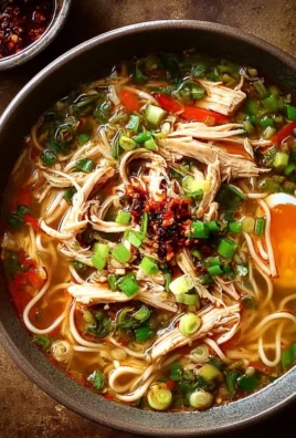 Bowl of Classic Ginger Garlic Chicken Noodle Soup garnished with fresh herbs.
