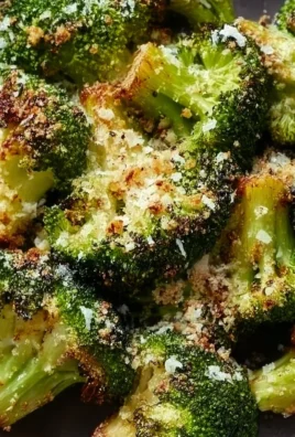 Roasted broccoli topped with parmesan cheese, served on a white plate.