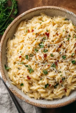 Creamy garlic parmesan orzo served in a bowl with garnished herbs