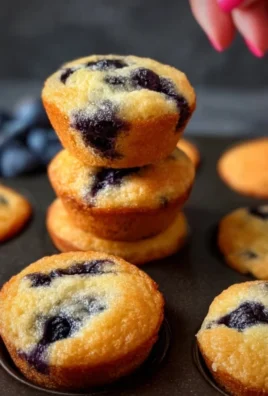 Freshly baked blueberry mini muffins on a cooling rack.