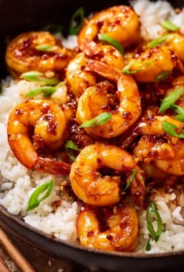 Plate of Honey Garlic Shrimp garnished with green onions and served over rice.