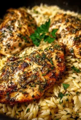 Plate of Instant Pot Lemon Herb Chicken served with orzo pasta and garnished with herbs.
