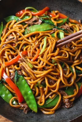A bowl of savory Lo Mein noodles topped with vegetables and sauce.