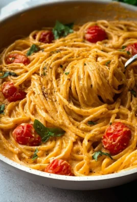 Creamy roasted tomato and garlic ricotta pasta dish garnished with fresh herbs.
