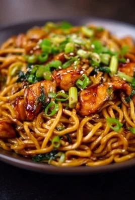 Sticky garlic chicken noodles dish served in a bowl with fresh herbs