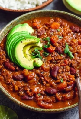 Delicious bowl of vegan chili topped with fresh herbs and avocado slices.