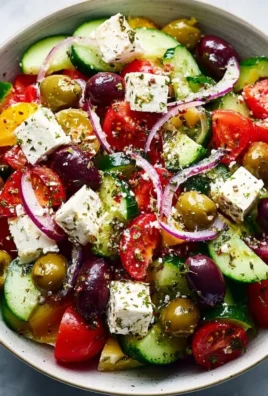 Freshly prepared Greek salad with tomatoes, cucumbers, olives, and feta cheese.