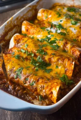 Cheesy beef enchiladas topped with melted cheese and served on a plate