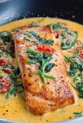 Creamy Tuscan Salmon topped with spinach and sun-dried tomatoes in a flavorful sauce.