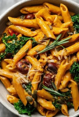 Bowl of creamy vegan pumpkin pasta topped with herbs and pumpkin seeds