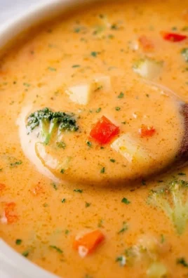 Bowl of creamy vegetable soup garnished with herbs and fresh vegetables
