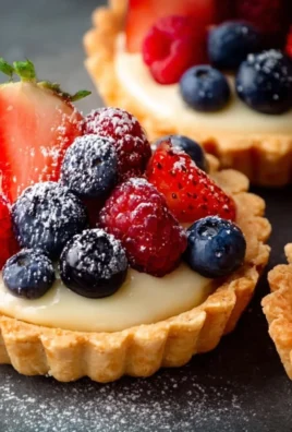 Mini fruit tarts topped with fresh berries and kiwi on a pastry crust