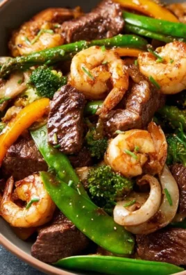 Steak and shrimp stir fry with vibrant vegetables on a plate