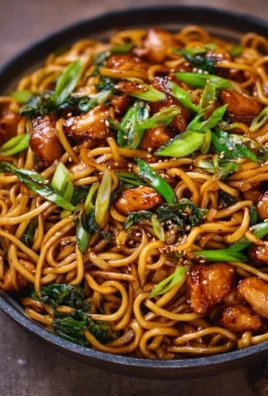 Sticky garlic chicken noodles dish garnished with green onions.