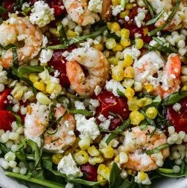 Colorful couscous salad with shrimp, corn, and feta cheese in a bowl.