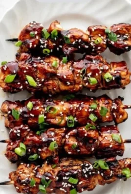 Delicious grilled teriyaki chicken skewers with vegetables on a white plate