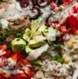 High-protein refried bean veggie bowl topped with fresh vegetables and spices.