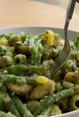 Potato and green bean salad in a bowl garnished with herbs