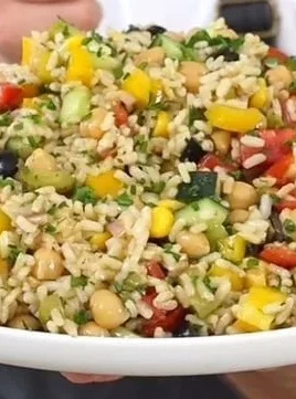 Colorful rice salad with fresh vegetables and herbs served in a bowl