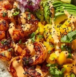A vibrant bowl featuring charred shrimp and fresh avocado slices.