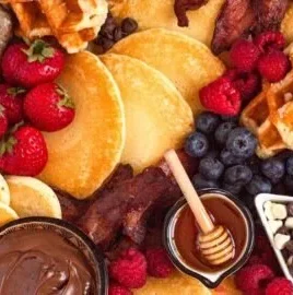 Colorful breakfast charcuterie board with fruits, cheeses, and pastries