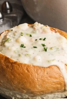 Bowl of creamy clam chowder with fresh clams and herbs garnished on top