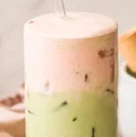Iced strawberry matcha latte in a glass with fresh strawberries and matcha powder
