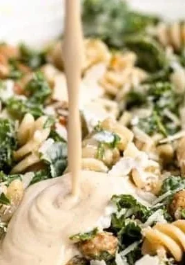 Delicious Kale Caesar Pasta Salad in a bowl with dressing and toppings