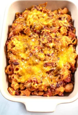 Delicious leftover chili mac dish garnished with cheese and herbs.