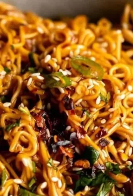 Bowl of spicy ramen noodles garnished with vegetables and spices