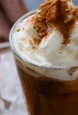 Delicious cinnamon roll iced coffee with whipped cream and a cinnamon sprinkle.